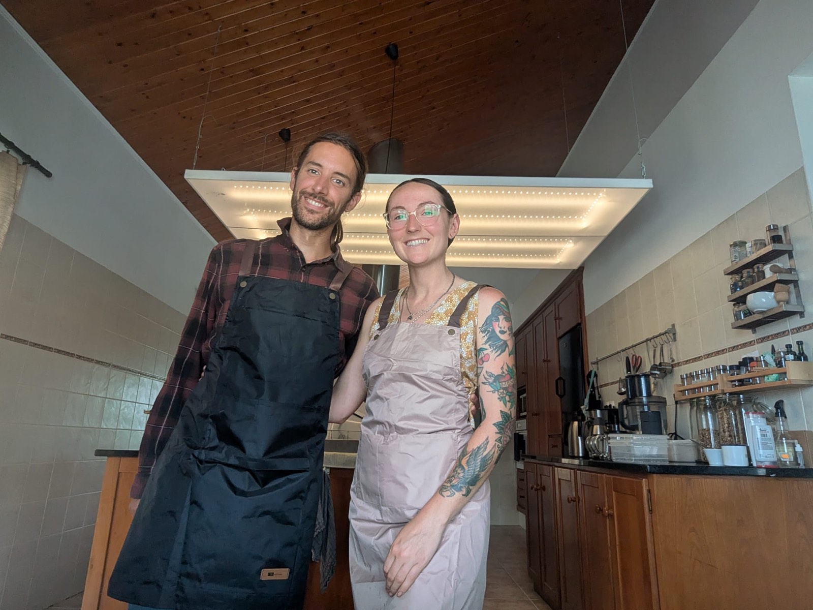 Lindsay and Chris standing together in their kitchen, wearing aprons