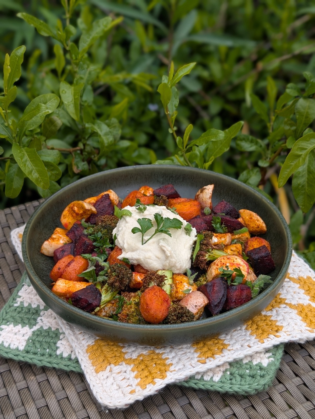 A bowl of roasted root vegetables topped with whipped hummus