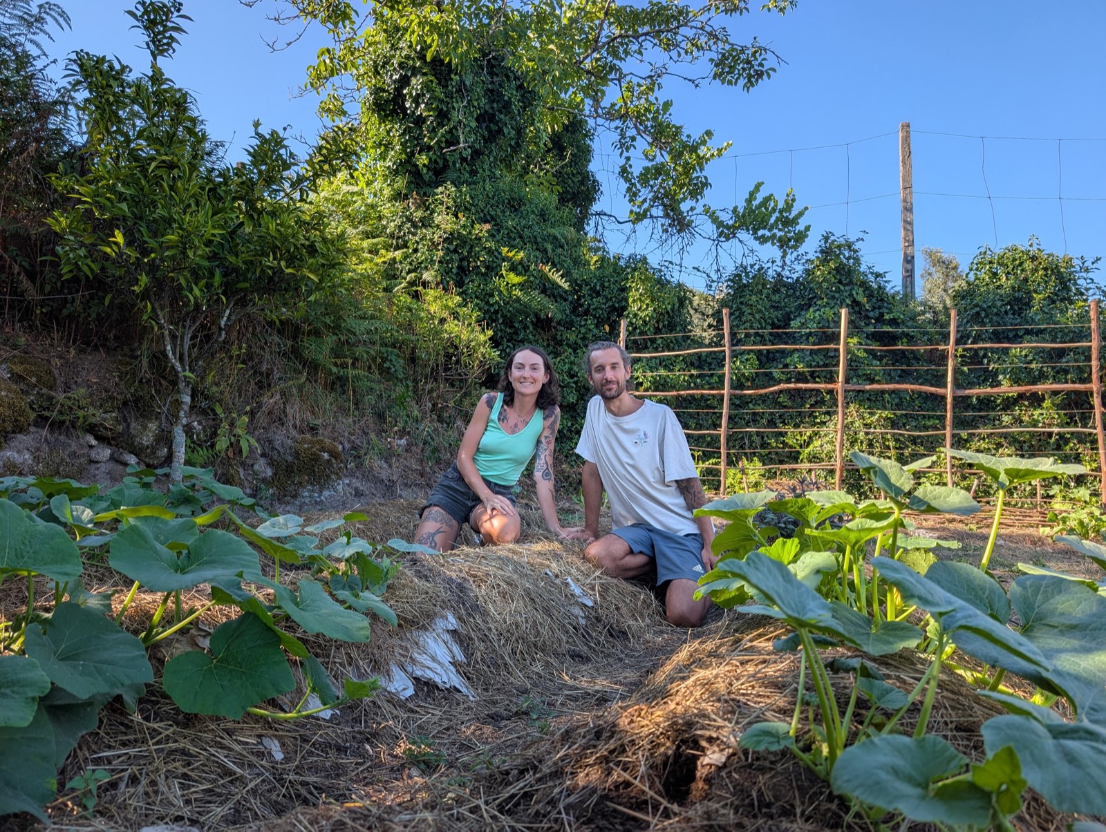 Lindsay and Chris kneeling together among squash plants in their garden