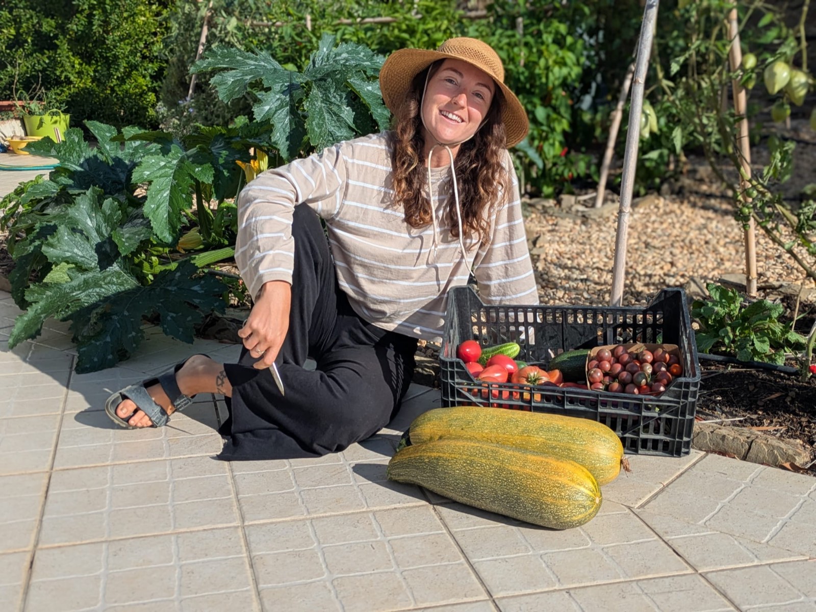 Portrait of Lindsay kneeling in the garden with a sun hat