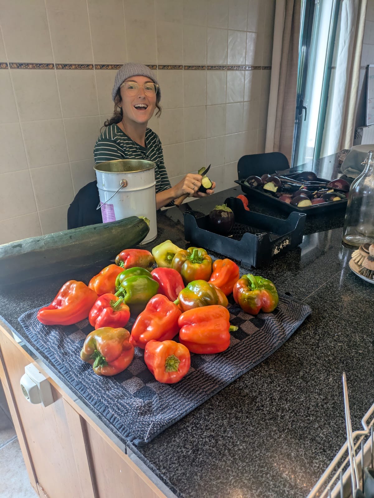 Lindsay in the kitchen with a counter full of freshly picked peppers
