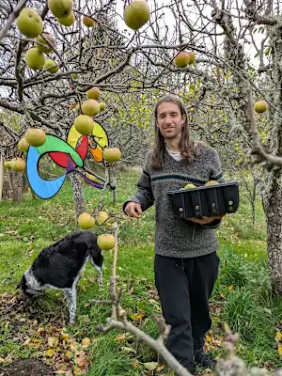 Chris picking apples in an orchard with a dog