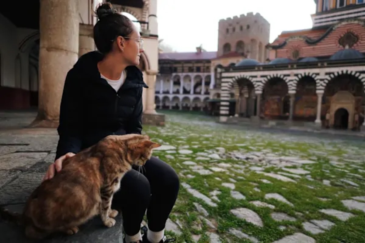 Lindsay sitting with a cat at a monastery courtyard
