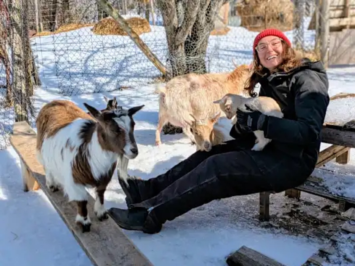 Lindsay sitting with goats in the snow